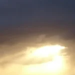 Sunlight breaking through dark clouds during a dramatic sky scene.
