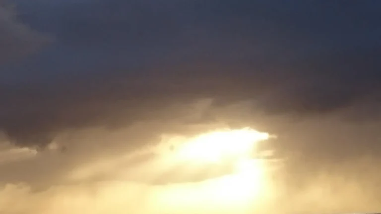 Sunlight breaking through dark clouds during a dramatic sky scene.
