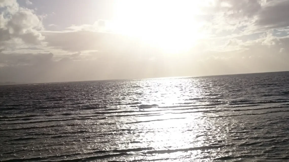 Sunset over the ocean with warm light reflecting on gentle waves.