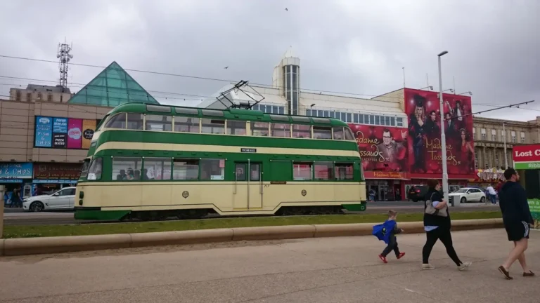 A guide to Blackpool and the first photo, showing a historic cream and green double-decker tram travelling along the Blackpool promenade, with buildings displaying a large advertisement for Madame Tussauds Wax Museum in the background.