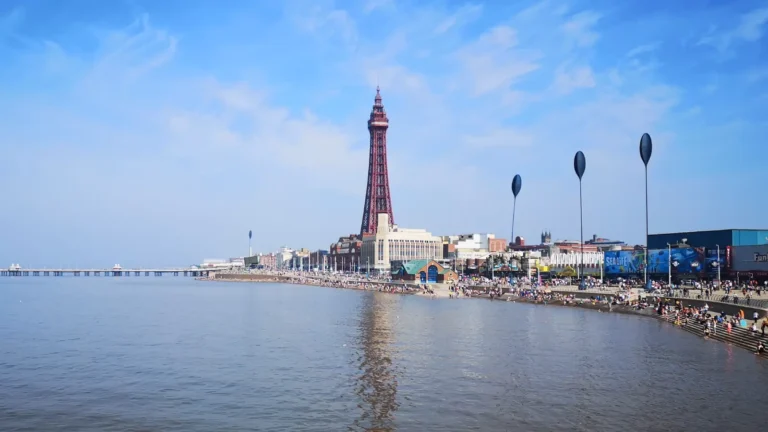 View of Blackpool Tower and the promenade photographed from the pier, with the beach and seaside buildings in the background