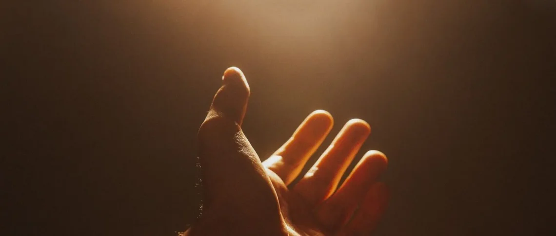 A raised hand reaching toward the light in a gesture of calling out to God for help.