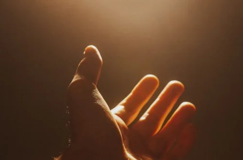 A raised hand reaching toward the light in a gesture of calling out to God for help.