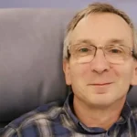 The author sits in a chair before his first chemotherapy session, smiling, still unaware of what lies ahead.