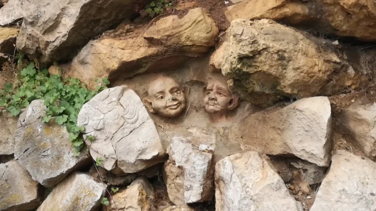Two late‑19th‑century stone faces carved by George Edwards on the limestone wall near Grove Park in Weston‑super‑Mare.