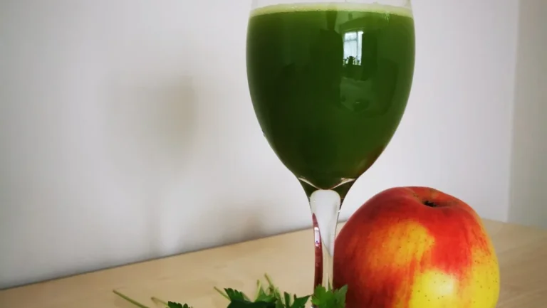 A glass of green vegetable juice, next to a bunch of parsley and an apple, part of the daily ritual during chemotherapy.
