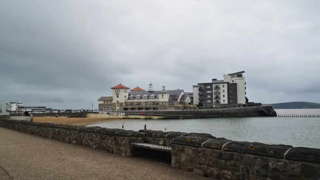 Buildings on Knightstone Island in Weston‑super‑Mare, including the “Float Together” complex, viewed from the seafront on a cloudy day.