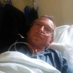 The author of the blog in a hospital bed, weakened, with an oxygen tube in his nose and his eyes half closed.