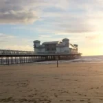 A romantic sunset view from the beach in Weston‑super‑Mare, with the Grand Pier silhouetted against the glowing horizon.