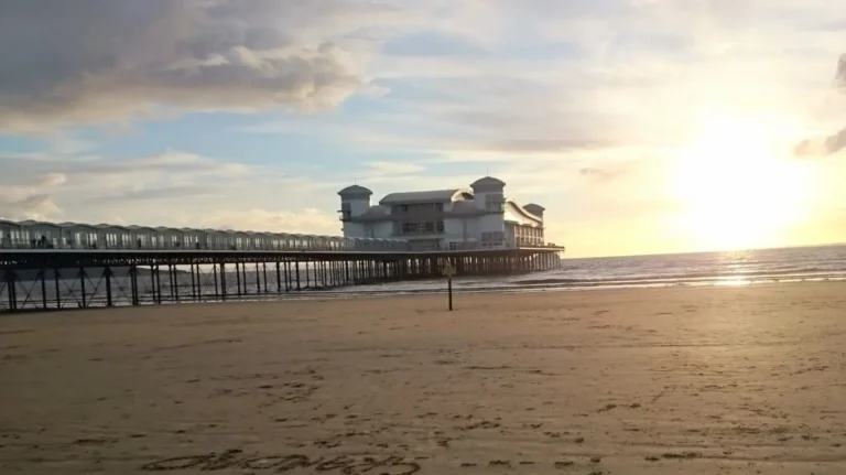 A romantic sunset view from the beach in Weston‑super‑Mare, with the Grand Pier silhouetted against the glowing horizon.