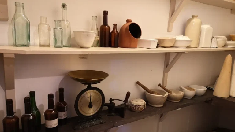 Two shelves in the former servants' kitchen at Shugborough Estate, filled with bottles, scales and bowls.
