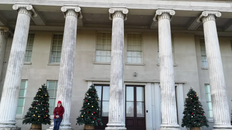 The neoclassical entrance of a Shugborough Estate building decorated with Christmas trees.