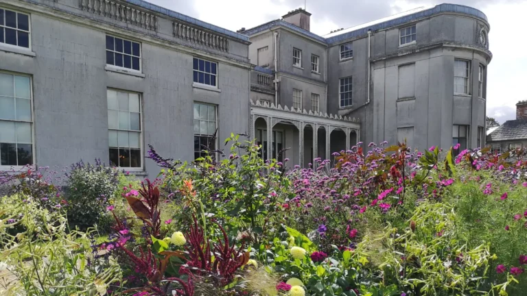 The garden-facing side of the main Shugborough Hall building with a flower border in front.