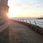 A sunset view from beside Stones Cafe in Weston‑super‑Mare, with the closed Anchor Head Hotel visible in the distance across the water.