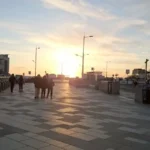 A sunset view from the promenade in Weston‑super‑Mare, looking toward Marine Bay with people walking along the waterfront.