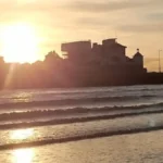 A sunset view from the promenade in Weston‑super‑Mare, with the buildings of Knightstone Island silhouetted against the glowing horizon.