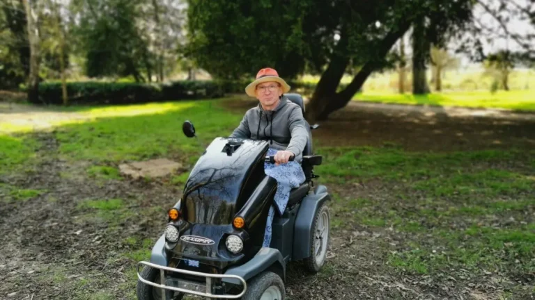 The author on a large Tramper scooter, taken at an angle, against the backdrop of trees at Shugborough Estate.