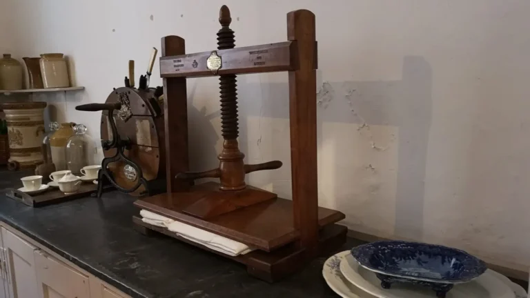 The interior of the former kitchen at Shugborough Estate with an old press and plates and cups on the countertop.