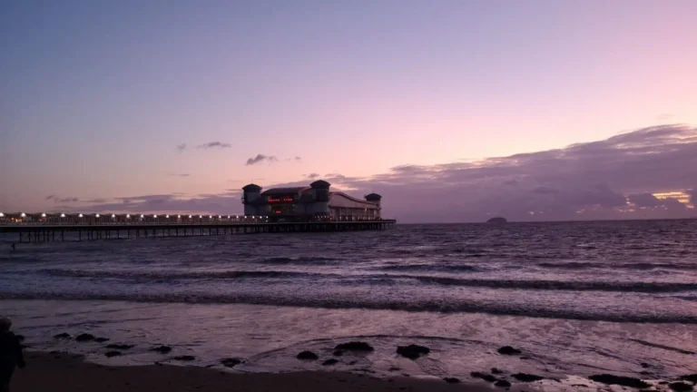 The Grand Pier in Weston‑super‑Mare illuminated at twilight, stretching over the calm sea beneath a purple‑pink sky.