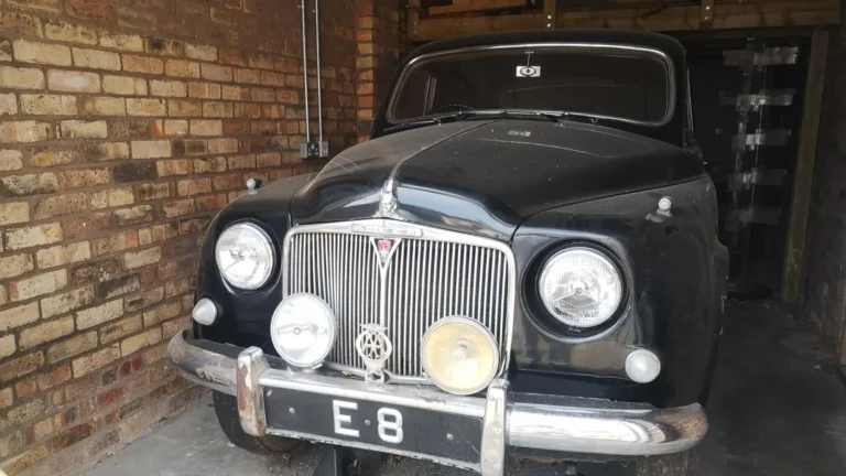 A vintage Rover car displayed inside a brick-walled garage at Shugborough Estate.