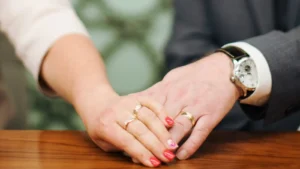The hands of a newly married couple, with their wedding rings prominently displayed.