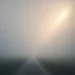 A foggy path stretching into the distance, with a ray of light breaking through — a quiet image of uncertainty and hope.
